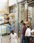 Guide showing the copper stills and oak barrels to a group inside the CIRKA distillery in Montreal