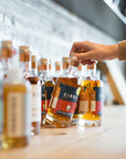 CIRKA spirit bottles on the bar with a hand reaching for a Navy Strength gin