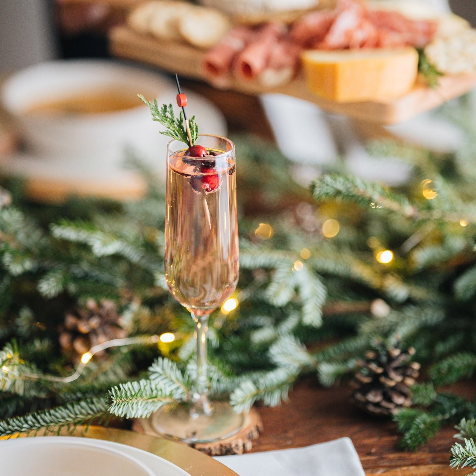 Champagne glass with a sprig of rosemary on a festive table with Christmas decorations.